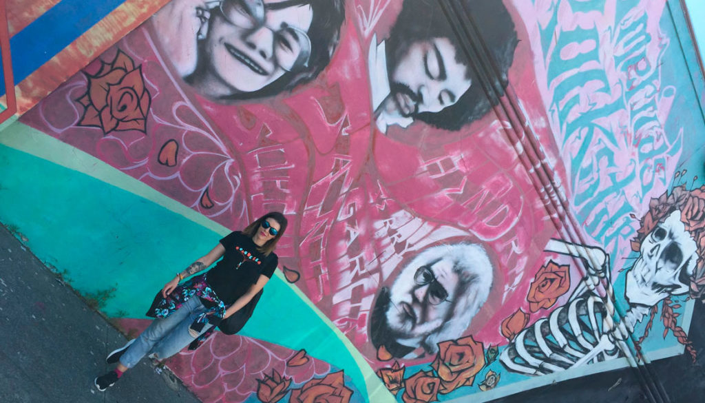 Jente poserer foran en vegg tagget med grafitti